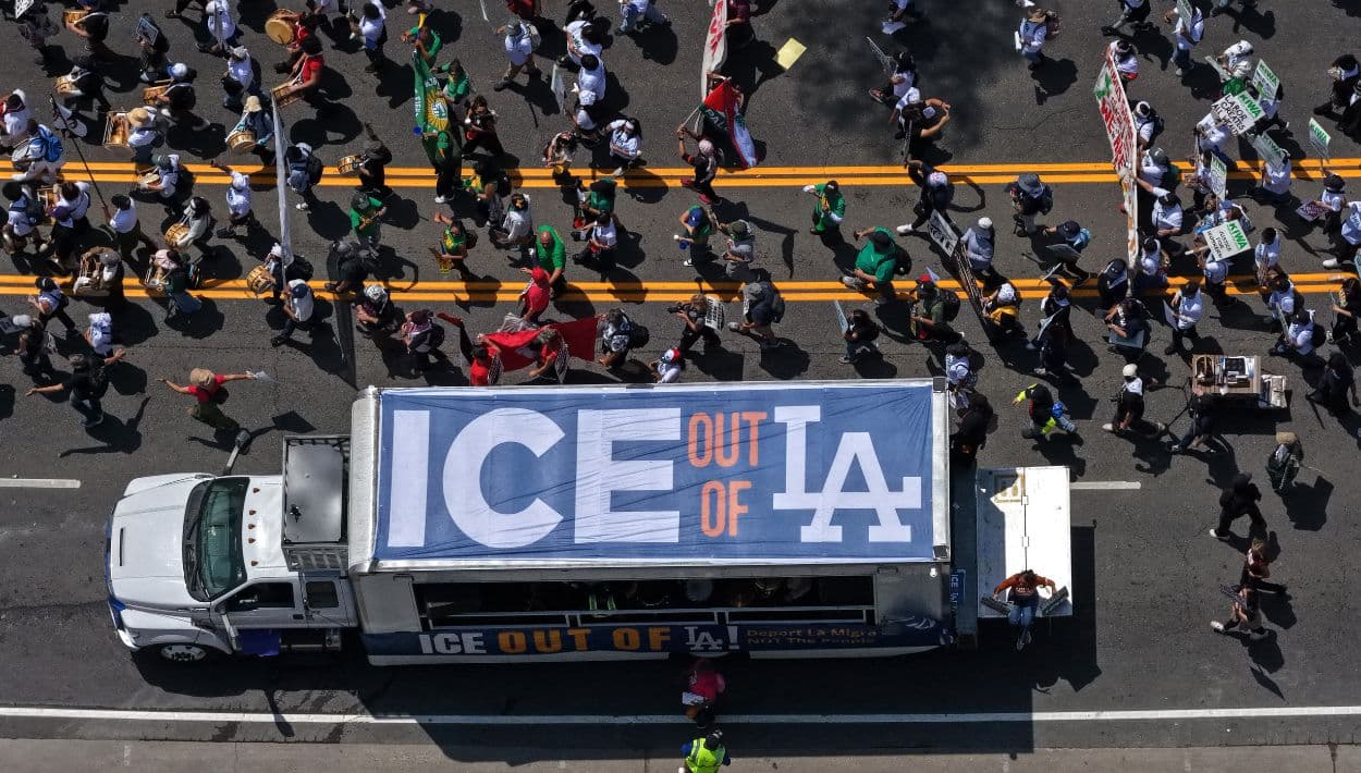 Activistas laborales marchan junto a un camión con una pancarta que dice “ICE Out of LA” durante la manifestación por el May Day.