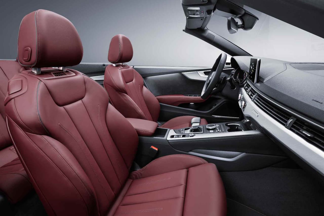 El interior del 
<b>A5 Cabriolet</b> muestra asientos y algunos detalles en 
<b>cuero</b> de color rojo oscuro. El volante y el instrumental mantienen el negro con detalles en el color exterior del auto, en este caso plateado.