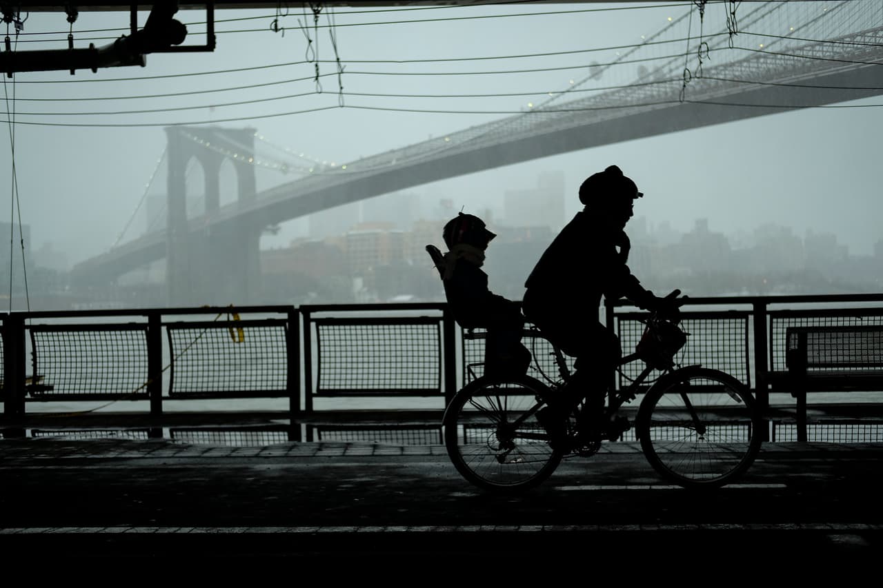Un ciclista se desplaza bajo una vía techada que lo protege de la nevada junto al East River de Nueva York.