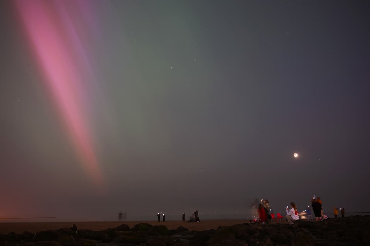 La gente se reúne para observar la aurora boreal, en New Brighton, Reino Unido. La tormenta solar más poderosa en más de dos décadas llegó a la Tierra, provocando espectaculares luces celestiales... y amenaza con posibles interrupciones en los satélites y las redes eléctricas si persiste durante el fin de semana.