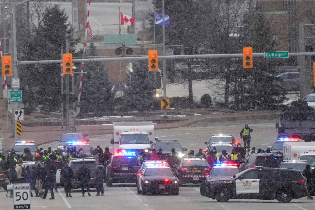 Policías forman filas de seguridad mientras hacen cumplir una orden judicial de desalojo de los manifestantes que bloquearon el tráfico en el puente Ambassador en Windsor, Canadá, el sábado 12 de febrero de 2022. Los manifestantes se alejaron cuando decenas de policías se acercaron poco después del amanecer. (Nathan Denette/The Canadian Press vía AP)