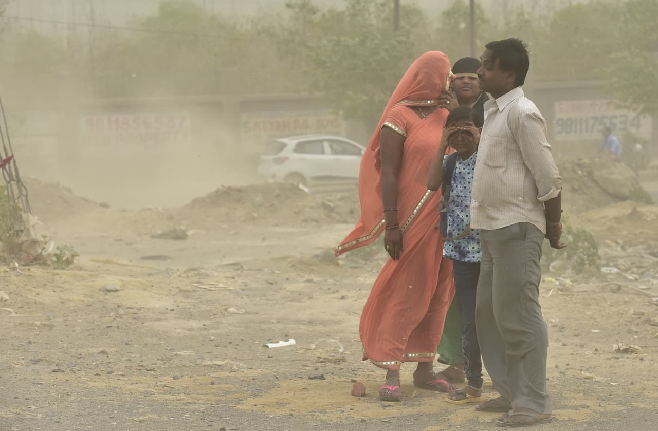 Una familia se cubre en medio de una repentina tormenta de polvo en Noida, India.
