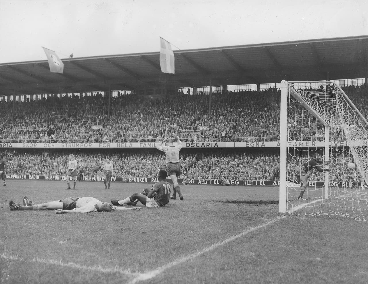 El portero sueco Kalle Svensson, a la derecha, intenta en vano detener el quinto gol de Brasil, anotado por Pelé, número 10, sentado en el suelo, en los minutos finales de la final de la Copa del Mundo en Estocolmo, Suecia, el 29 de junio de 1958. El lateral izquierdo sueco Sven Axbom yace en el suelo a la izquierda y el mediocampista derecho sueco Reino Borjesson se aleja con los brazos en alto. Brasil derrotó a Suecia por cinco goles a dos.
