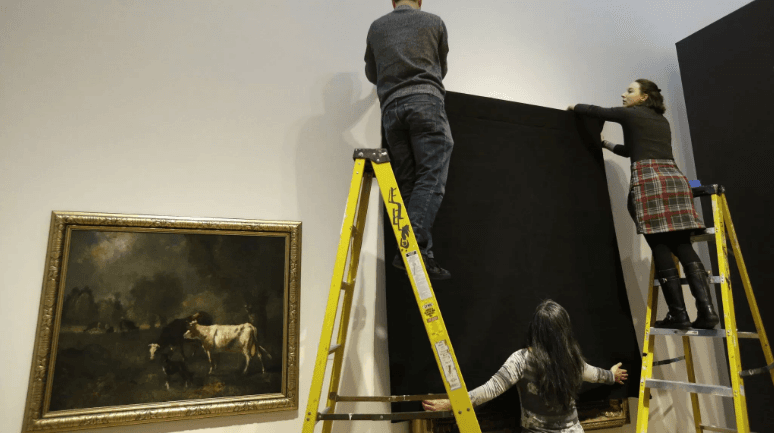 Operarios del museo tapan obras realizadas por inmigrantes.