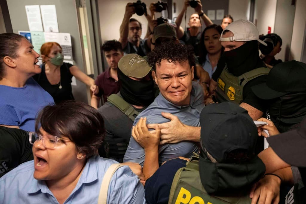 Agentes federales detienen a Carlos Javier Lopez Benitez (centro), quien es oriundo de Paraguay, mientras empujan a su hermana Porfiria Lopez (izquierda), quien es ciudadana estadounidense, afuera de un tribunal de inmigración en el edificio federal Jacob K. Javits, en Nueva York, el miércoles 16 de julio de 2025. (AP Foto/Yuki Iwamura)