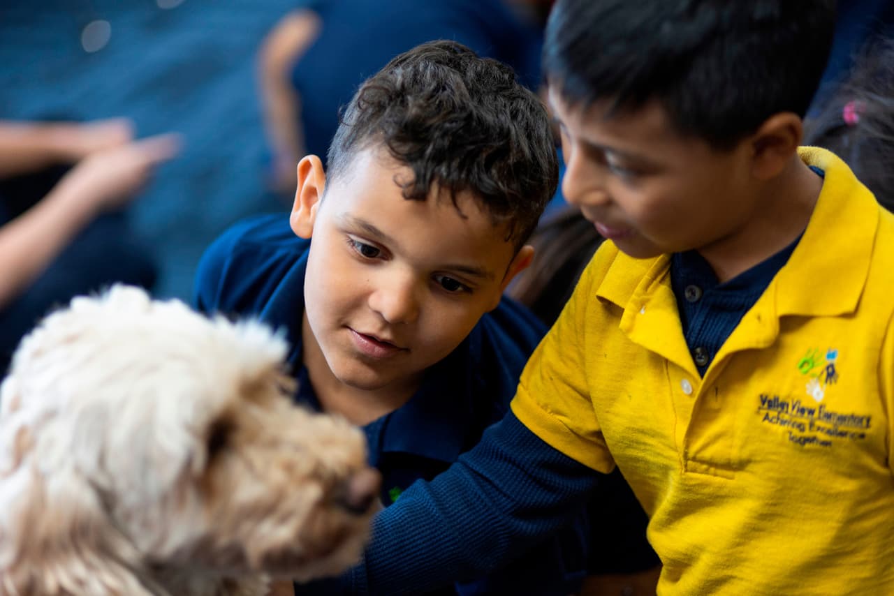 Kaleb, en el centro, acaricia a Sage, una perra de terapia, en la escuela primaria Valley View el 29 de abril de 2026 en Columbia Heights, Minnesota. (Ellen Schmidt/MinnPost via AP)