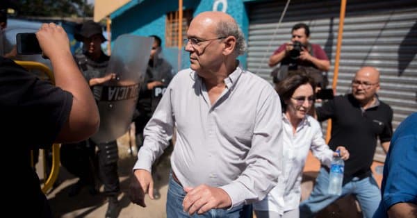 Carlos Fernando Chamorro y sus esposa tratan de evadir la policía antidisturbios cerca de la entrada principal de la sede de la policía en Managua, Nicaragua, el 15 de diciembre de 2018.