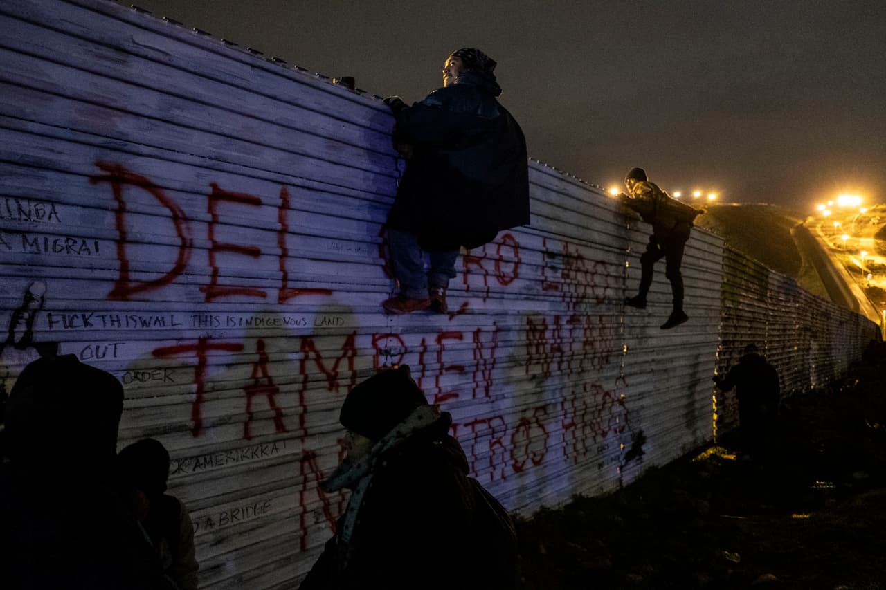 Migrantes mirando por encima de la valla fronteriza antes de intentar cruzar de Tijuana a San Diego.