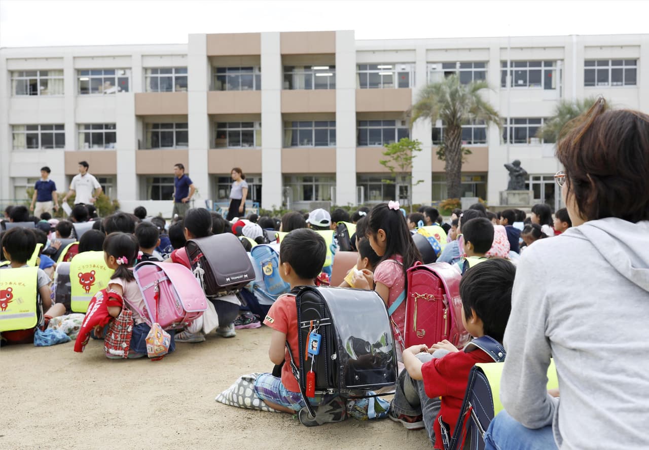 Students sit on a playground after they were evacuated from school building after an earthquake at Ikeda elementary school in Ikeda, Osaka prefecture, western Japan, in this photo taken by Kyodo June 18, 2018. Mandatory credit Kyodo/via REUTERS ATTENTION EDITORS - THIS IMAGE WAS PROVIDED BY A THIRD PARTY. MANDATORY CREDIT. JAPAN OUT. NO COMMERCIAL OR EDITORIAL SALES IN JAPAN.