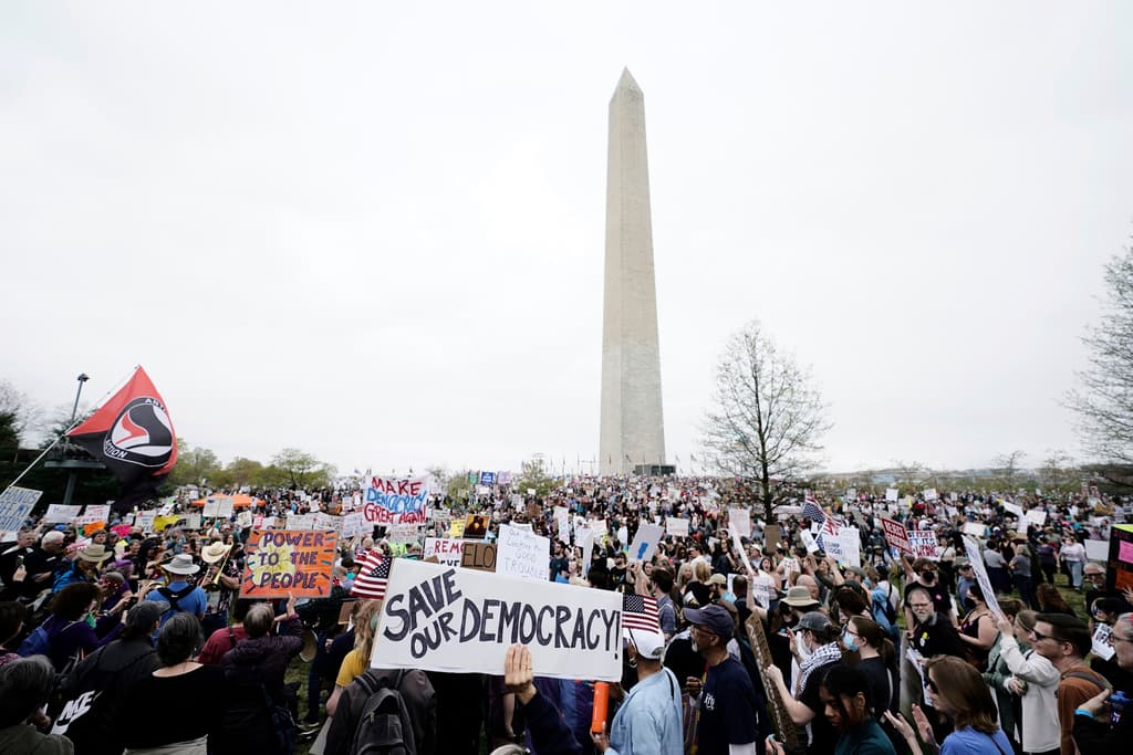 Demonstrators hold up signs during a "Hands Off!" protest against President Donald Trump at the Washington Monument in Washington, Saturday, April 5, 2025. (AP Photo/Jose Luis Magana)
