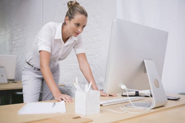 Párate con los pies separados. Colócate lo suficientemente lejos del escritorio, de modo tal que sólo puedas alcanzarlo con los brazos extendidos. Flexiona las caderas tomándote de la mesa.