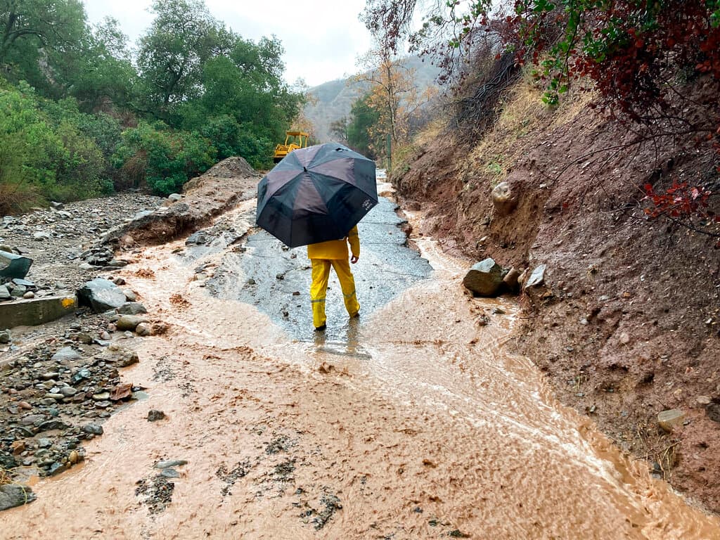 Un residente local examina los daños de una carretera arrasada en el Cañón Silverado, California, el martes 14 de diciembre de 2021. En el condado de Orange, al sur de Los Ángeles, unas 800 casas del cañón estaban bajo órdenes de evacuación el martes después de que se emitiera una advertencia de inundación repentina y se informara de deslizamientos de tierra en la zona, calcinada por el
<a href="https://www.univision.com/local/los-angeles-kmex/incendio-bond-destruye-mas-de-3-600-acres-en-california">incendio forestal de Bond en 2020</a>.