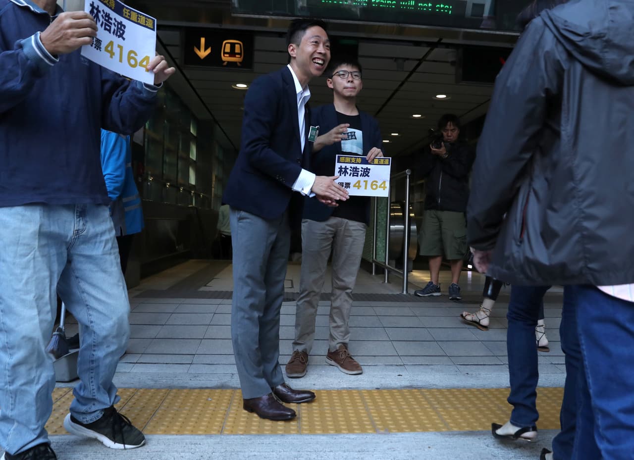 El candidato ganador Kelvin Lam junto al activista Joshua Wong agaradece a sus votantes. Los defensores del cambio político tienen la intención de utilizar esta victoria para demostrar que el pueblo de Hong Kong
<b> </b>quiere que el gobierno local tome en cuenta sus puntos de vista sobre la gestión del territorio semiautónomo.