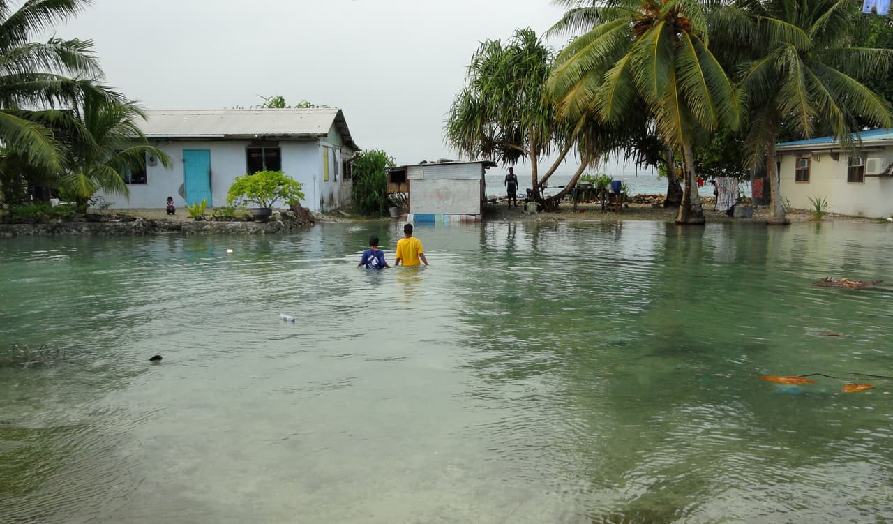 Two local residents wade through flooding caused by high ocean tides in low-lying parts of Majuro Atoll, the capital of the Marshall Islands, on February 20, 2011. Extreme high tides flooded parts of the low-lying Marshall Islands capital Majuro with a warning of worse to come because of rising sea levels. Several areas of the city were flooded and forecasters predicted more to come on before the current high tide levels ease. AFP PHOTO / Giff Johnson (Photo credit should read GIFF JOHNSON/AFP/Getty Images)