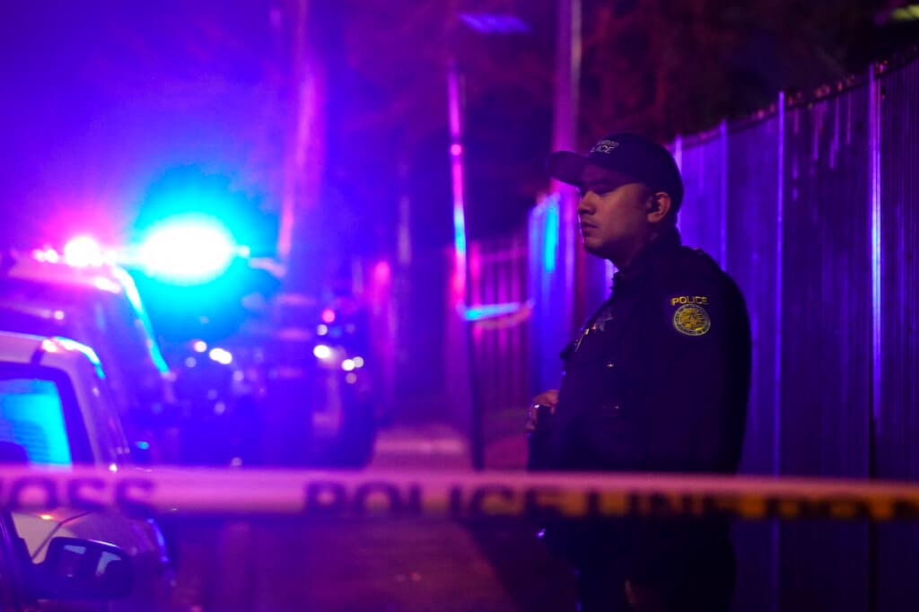 Un oficial de policía de Sacramento se para detrás de la cinta policial que bloquea la calle cerca de la escena de un tiroteo en Sacramento, California, el lunes 28 de febrero de 2022.