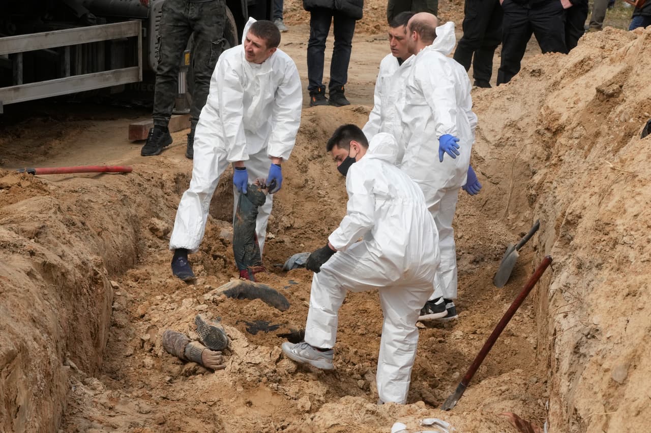 Hombres con equipo de protección exhuman los cuerpos de los civiles asesinados en Bucha, en las afueras de Kiev, Ucrania, el viernes 8 de abril de 2022.