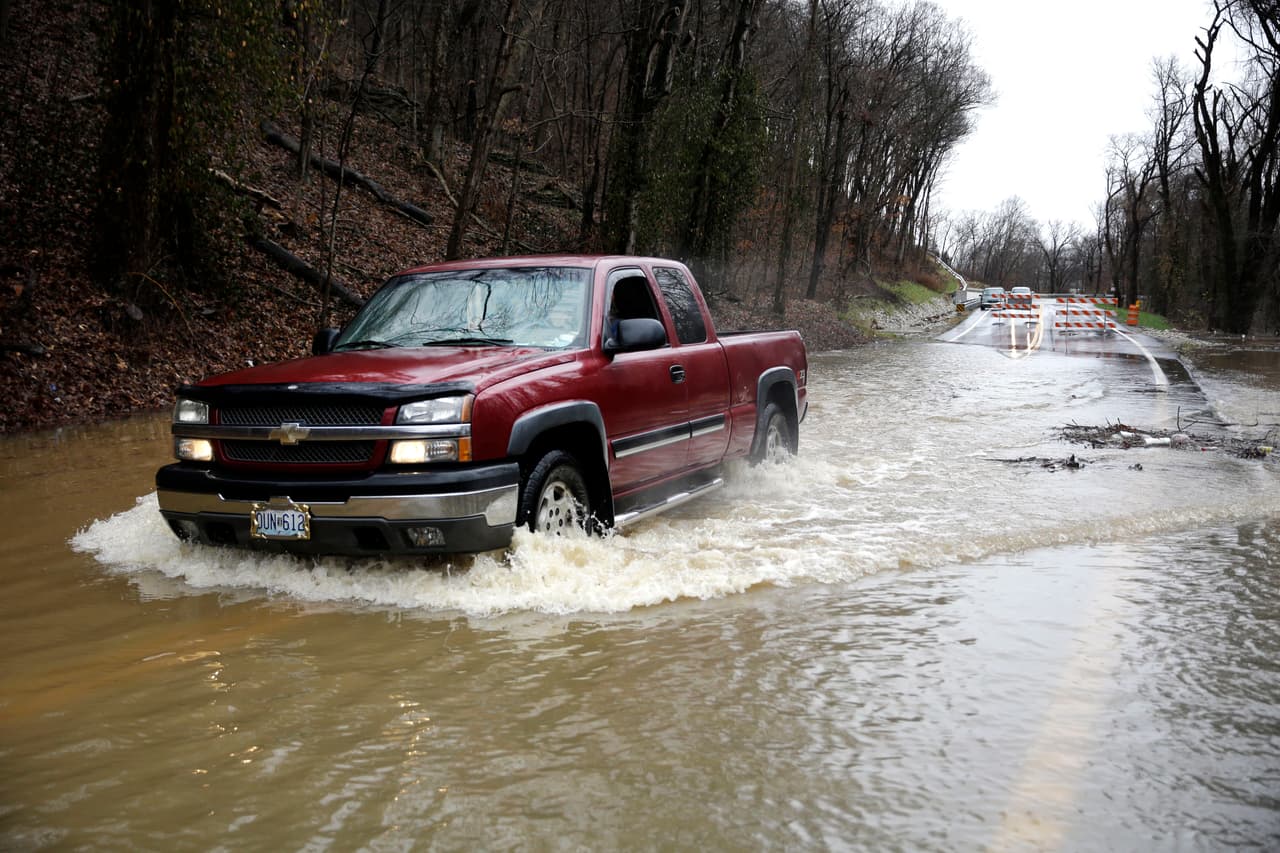 El conductor de una camioneta se desplaza lentamente en un camino cerrado por inundación en Missouri.