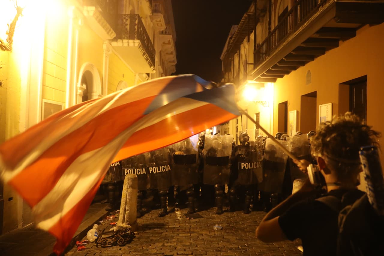 Manifestante enfrentandose a la policía con una bandera