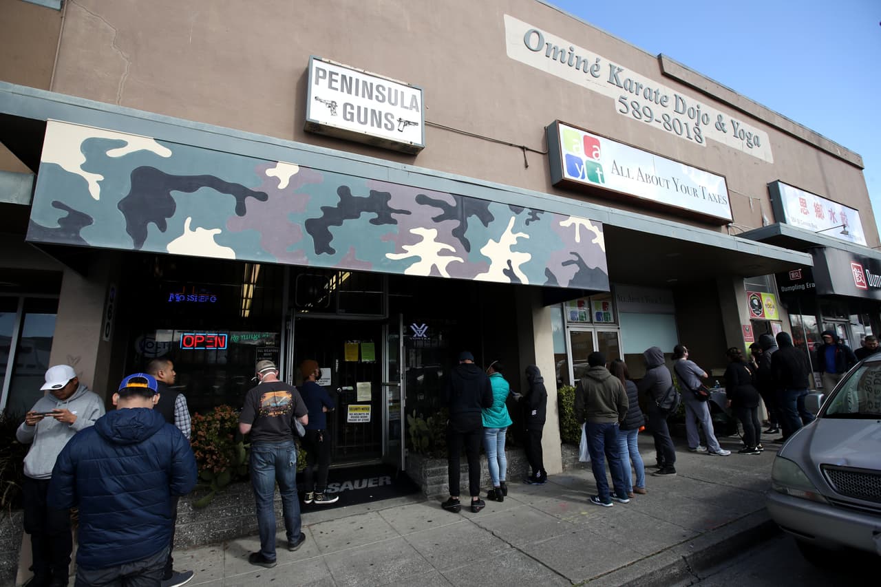 El anuncio del toque de queda también hizo que los residentes realizaran compras de pánico en las armerías. En la imagen, decenas de personas esperan esperan en fila afuera de Peninsula Guns and Tactical, una tienda de armas en San Bruno, California.