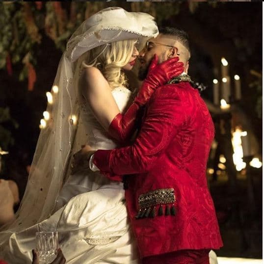 En el video podemos ver a la reina del pop portar distintos vestuarios, pero es casi al final que vemos a Madonna vestida de novia y a Maluma con un traje color rojo.