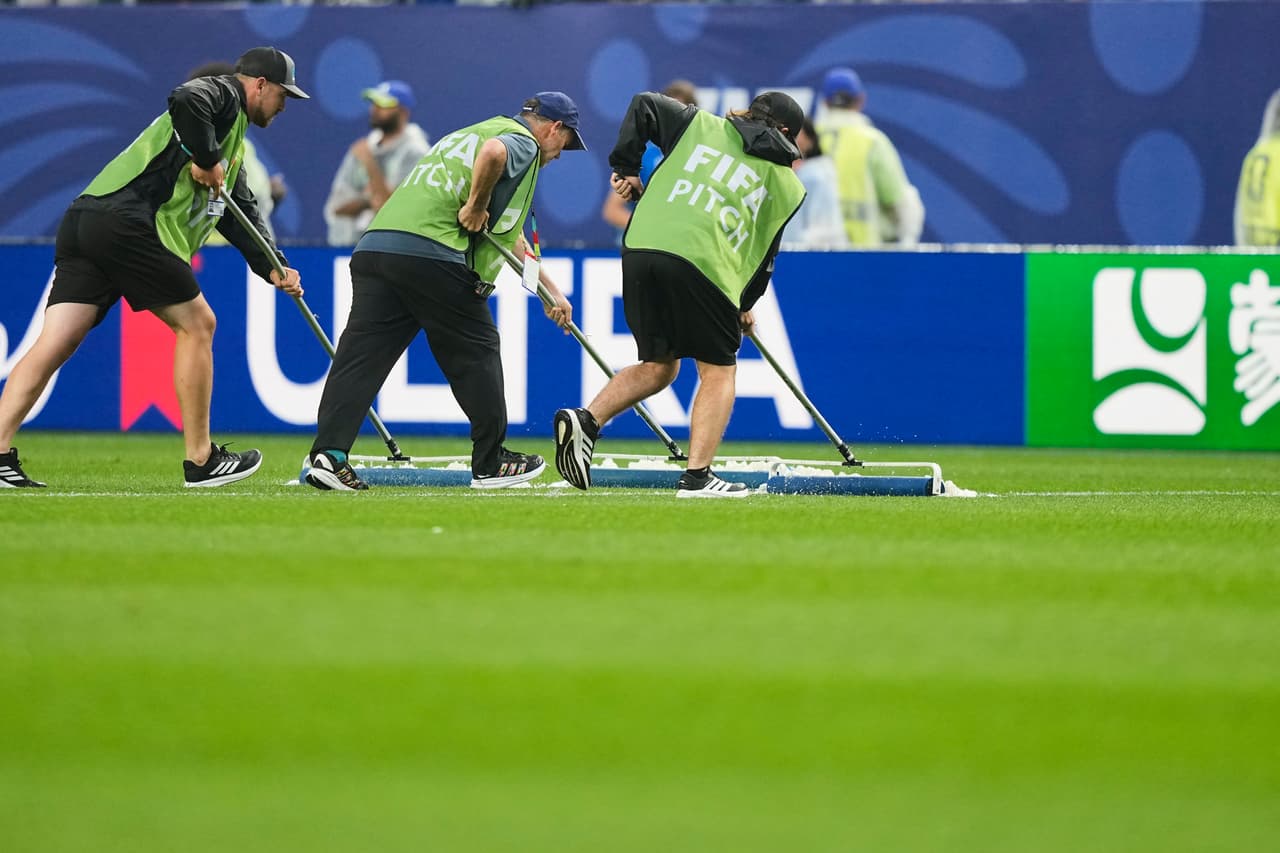Unos trabajadores retiran el exceso de agua del terreno de juego tras una interrupción por mal tiempo durante el partido de fútbol del Grupo I de la Copa del Mundo entre Francia e Irak en Filadelfia, el lunes 22 de junio de 2026.