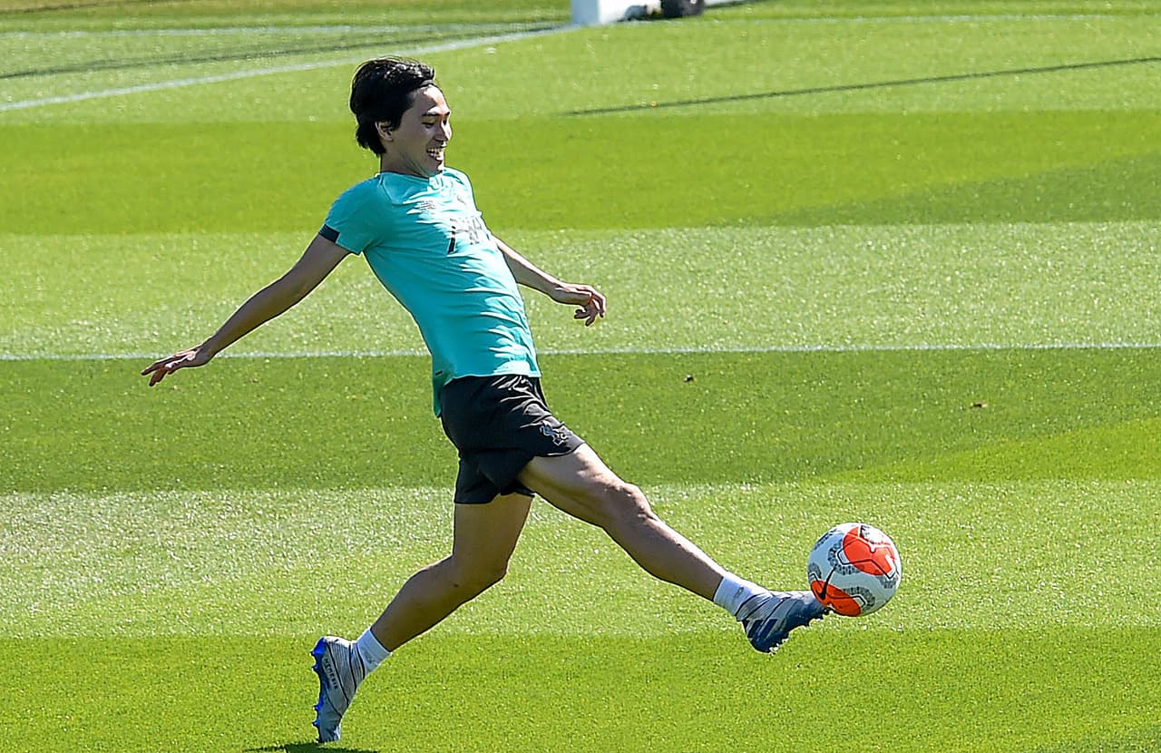 Takumi Minamino se estira por el balón para recibirlo de aire sin que caiga al suelo.