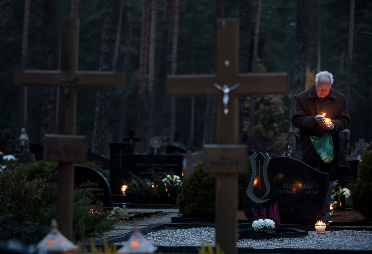 <b>Lituania.</b> Un hombre enciende una vela en el cementerio de Vilna, la ciudad capital.