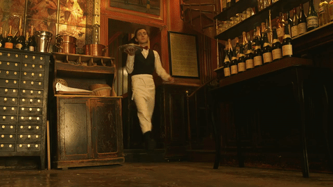 El perro hace que se rompa la mesa con naranjas y el mesero se tropieza con ellas.