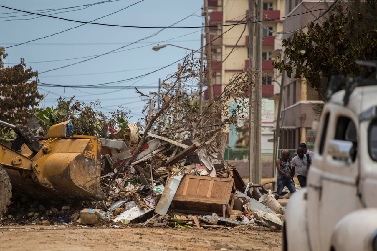 Una pala mecánica remueve restos de árboles, basura y muebles dañados por los vientos y la inundación.