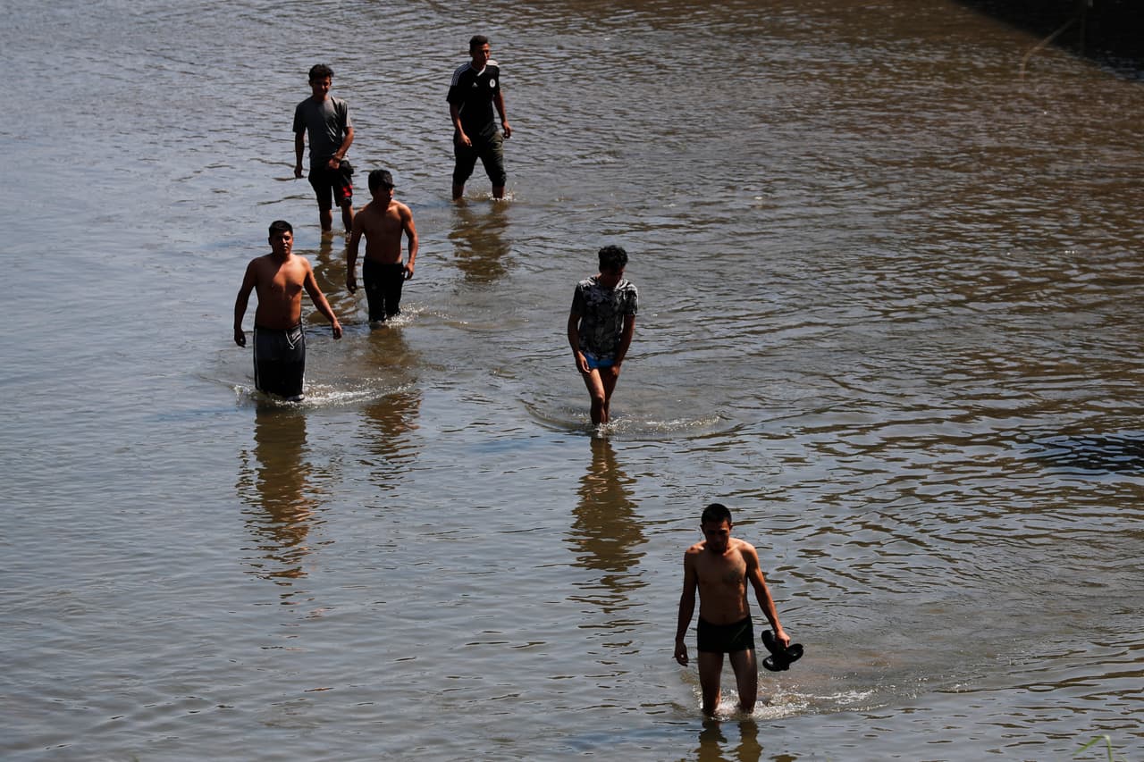 Un grupo de migrantes hondureños camina en el río Suchiate este domingo bajo la mirada vigilante de la Guardia Nacional de México.