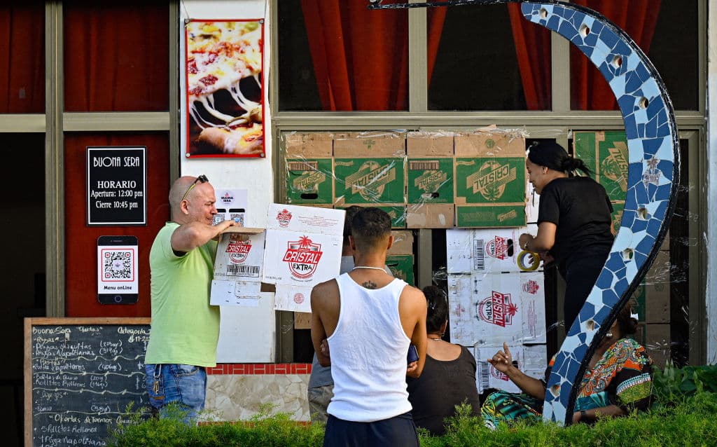 Hasta con cartón, comerciantes protegían las ventanas de comercios en La Habana, Cuba, este miércoles en la mañana, previo al paso del huracán Rafael.