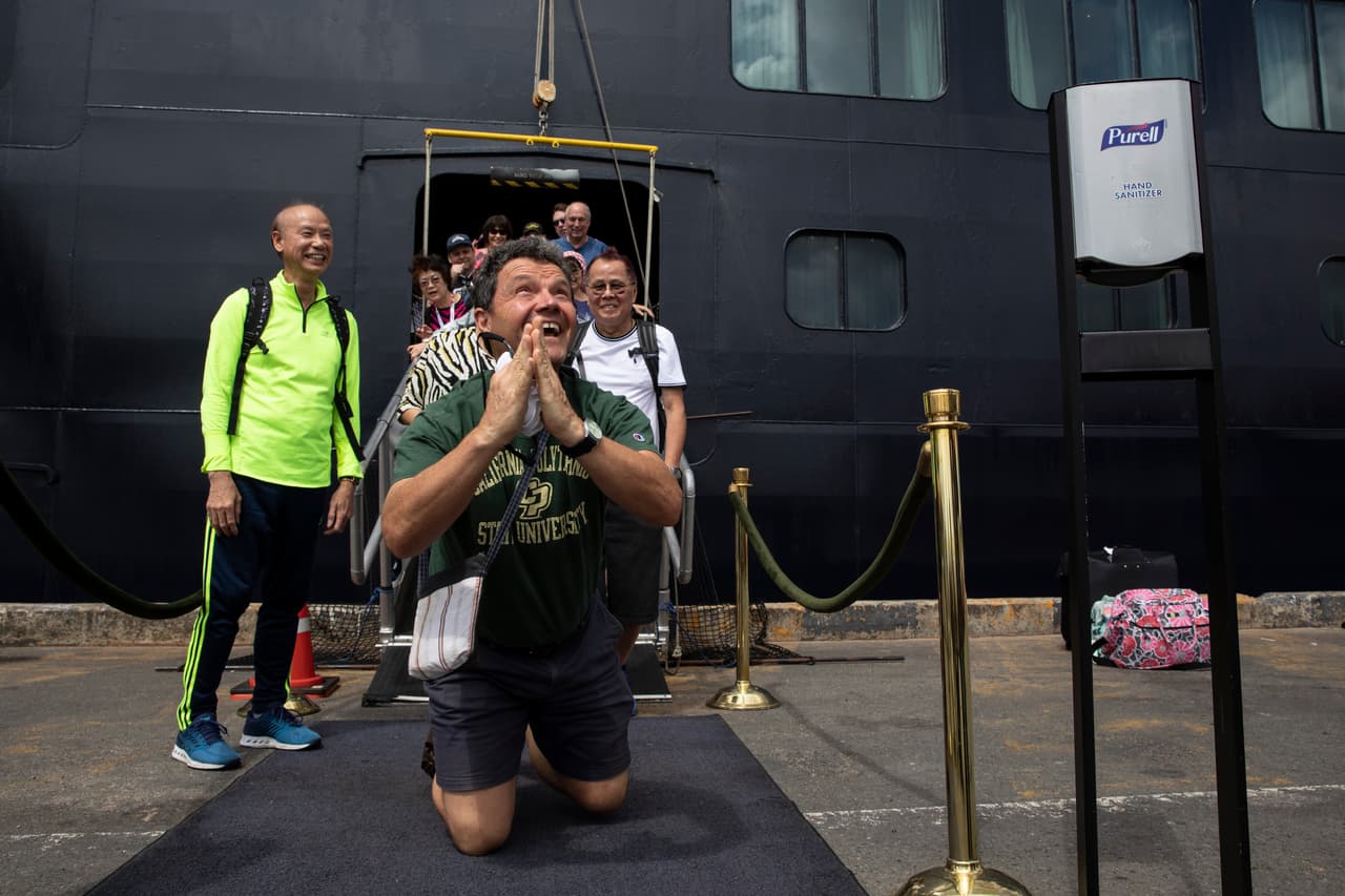 Aquí, el pasajero John Miller, de Seattle, Washington, emocionado y rezando en su desembarco del crucero MS Westerdam. El barco completamente libre del Coronavirus (COVID-19.) llevaba 1,455 pasajeros y 802 tripulantes a bordo.