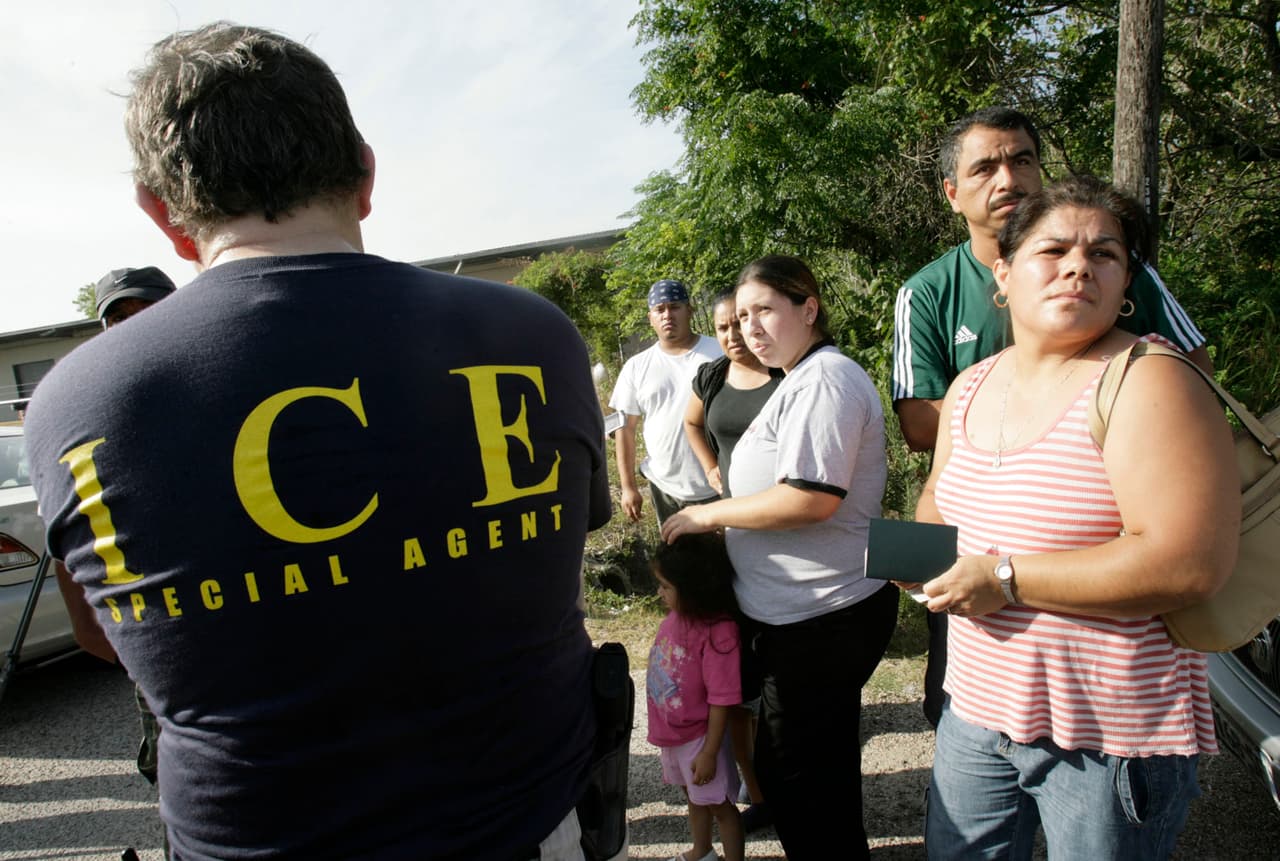 Un agente federal del Servicio de Inmigración y Aduanas (ICE) habla con un grupo de personas durante una redada en un sector de Los Ángeles, California.