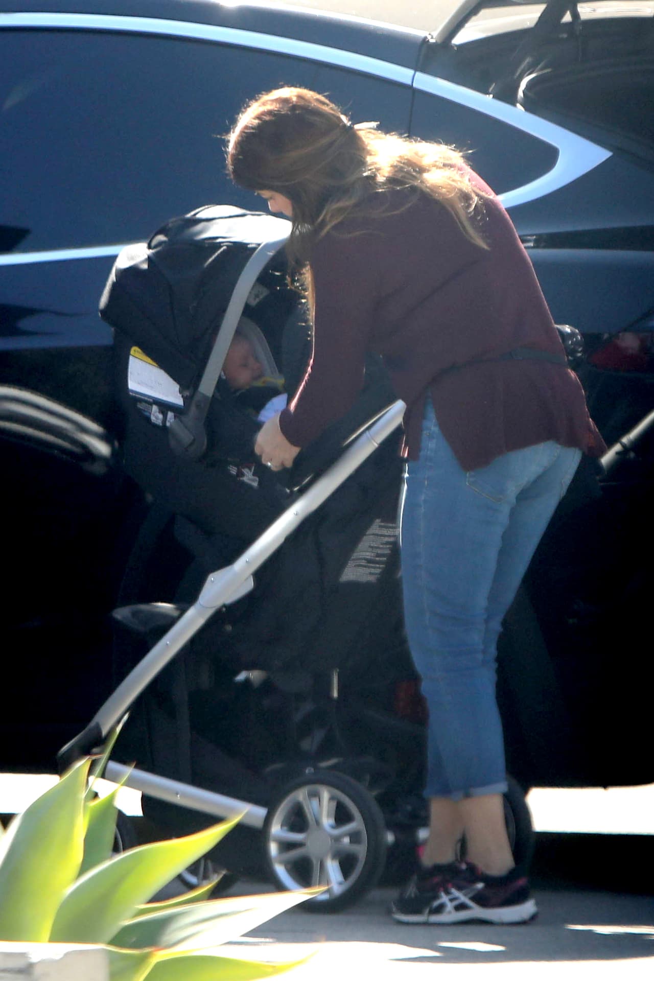 La niñera asegurándose que el pequeño esté bien, listo para meterlo al auto.