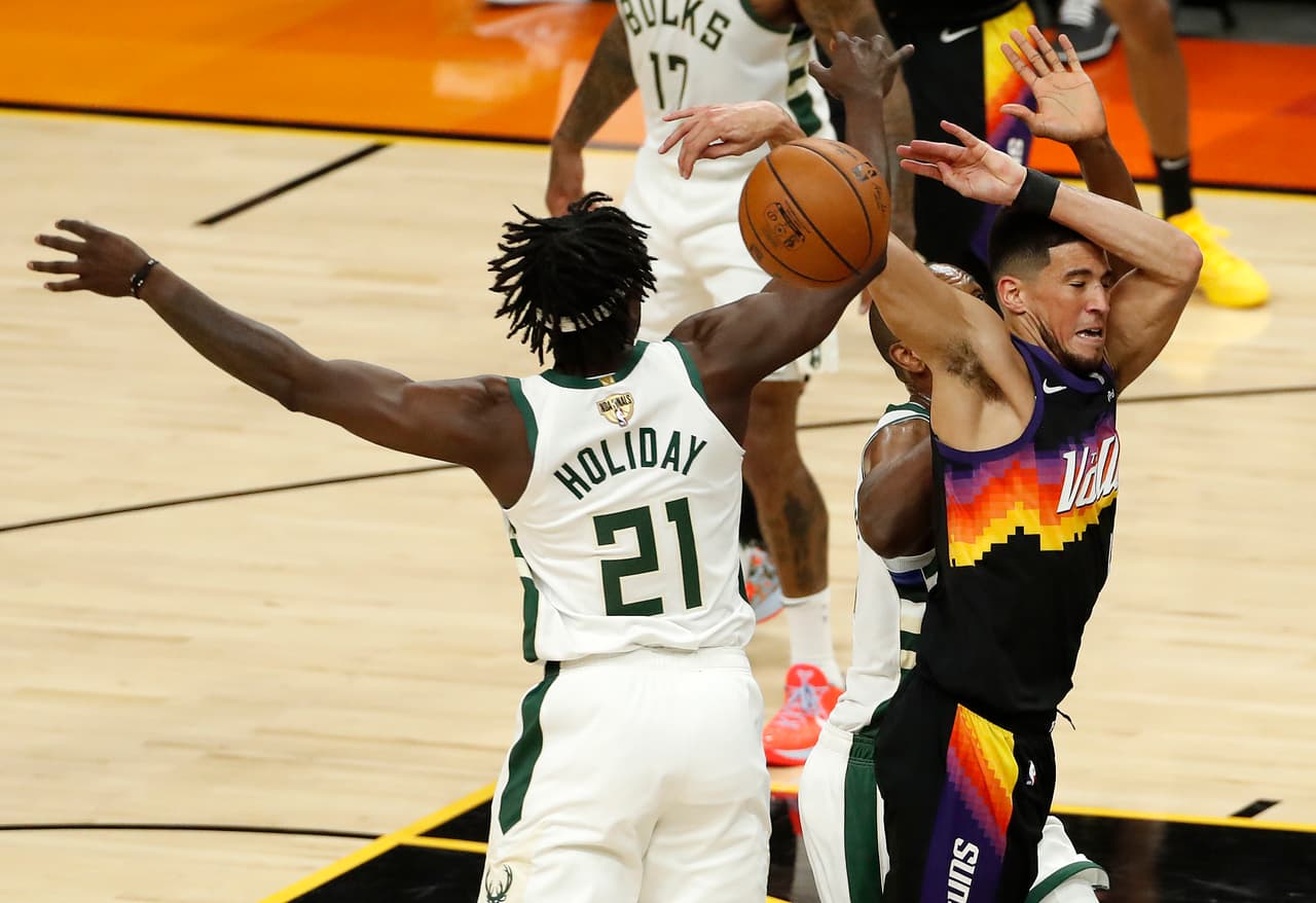 Devin Booker # 1 de los Phoenix Suns recibe una falta de Jrue Holiday # 21 de los Milwaukee Bucks durante el primer cuarto del Juego Uno de las Finales de la NBA.