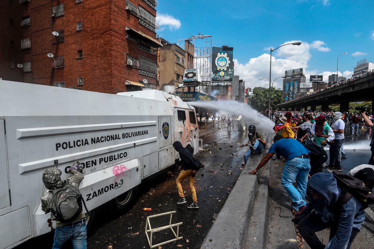 La ‘Ballena’, vehículo antimotines que dispara agua a presión, es golpeada por los manifestantes opositores.