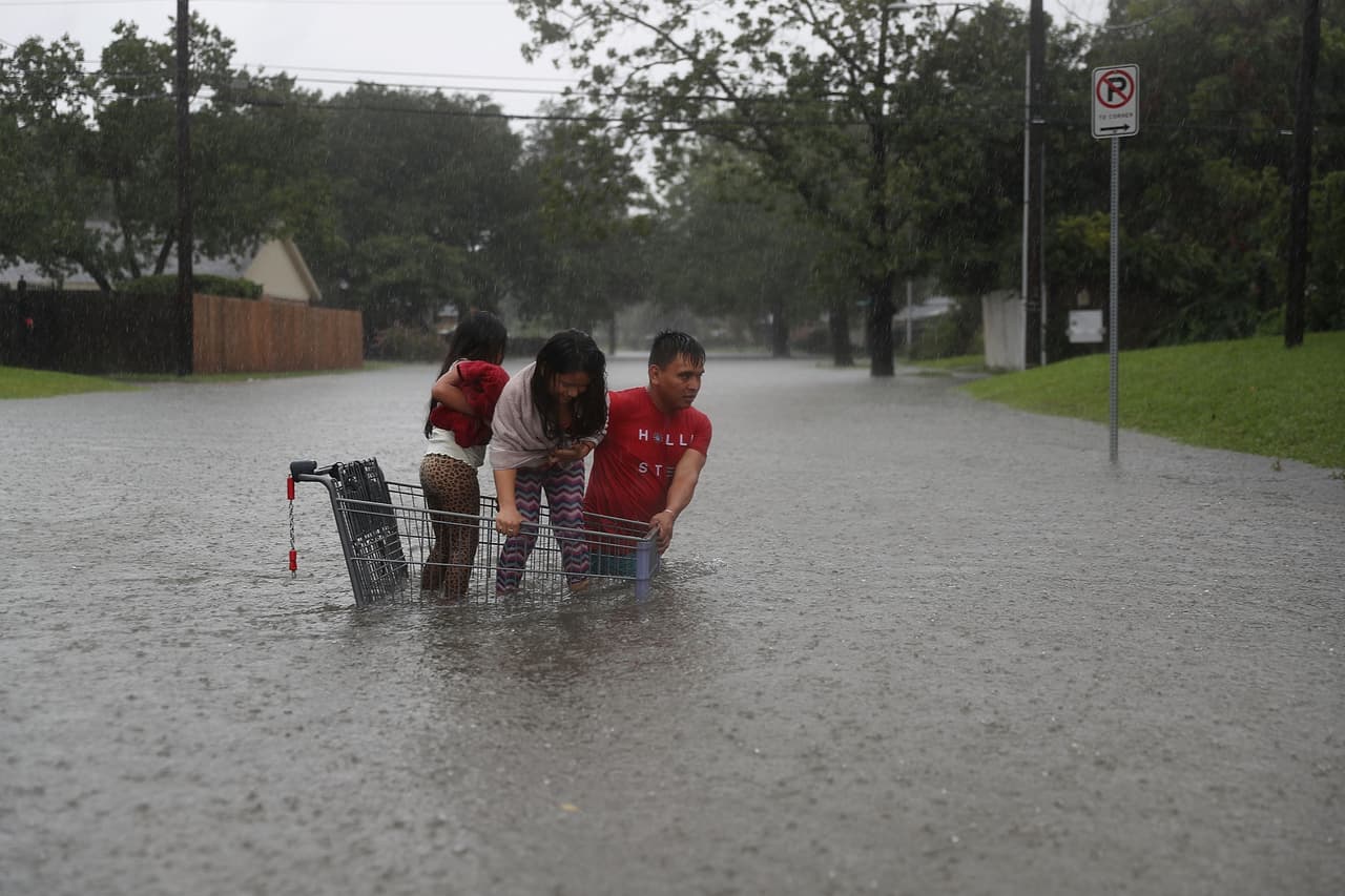 Un carro de marcado sirve de refugio para unos niños en una calle inundada.
