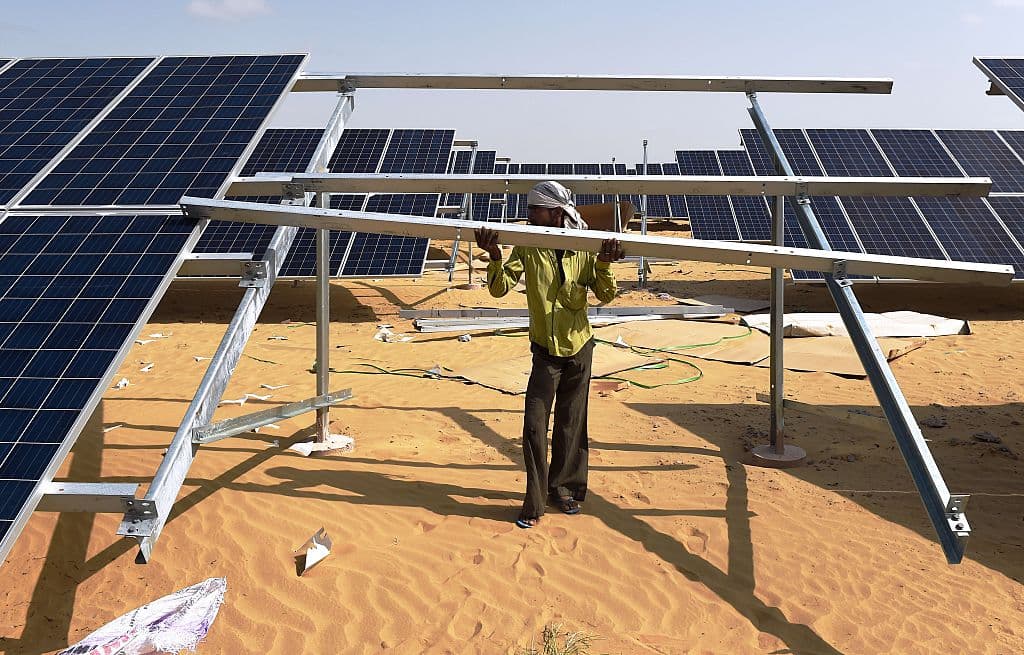 TO GO WITH: Climate-warming-COP21-India-energy-solar, FOCUS by Annie Banerji In this photograph taken on August 23, 2015, an Indian engineer fixes a solar panel into position at the under construction Roha Dyechem solar plant at Bhadla some 225 kms north of Jodhpur in the western Indian state of Rajasthan. Under a blistering sun, workers install a sea of solar panels in a north Indian desert as part of the government's clean energy push --- and its trump card at upcoming climate change talks in Paris. AFP PHOTO/MONEY SHARMA (Photo credit should read MONEY SHARMA/AFP/Getty Images)