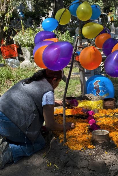 Los familiares de los difuntos cubren las tumbas de flores y adornos, que van desde los globos hasta las calaveritas de dulce.
