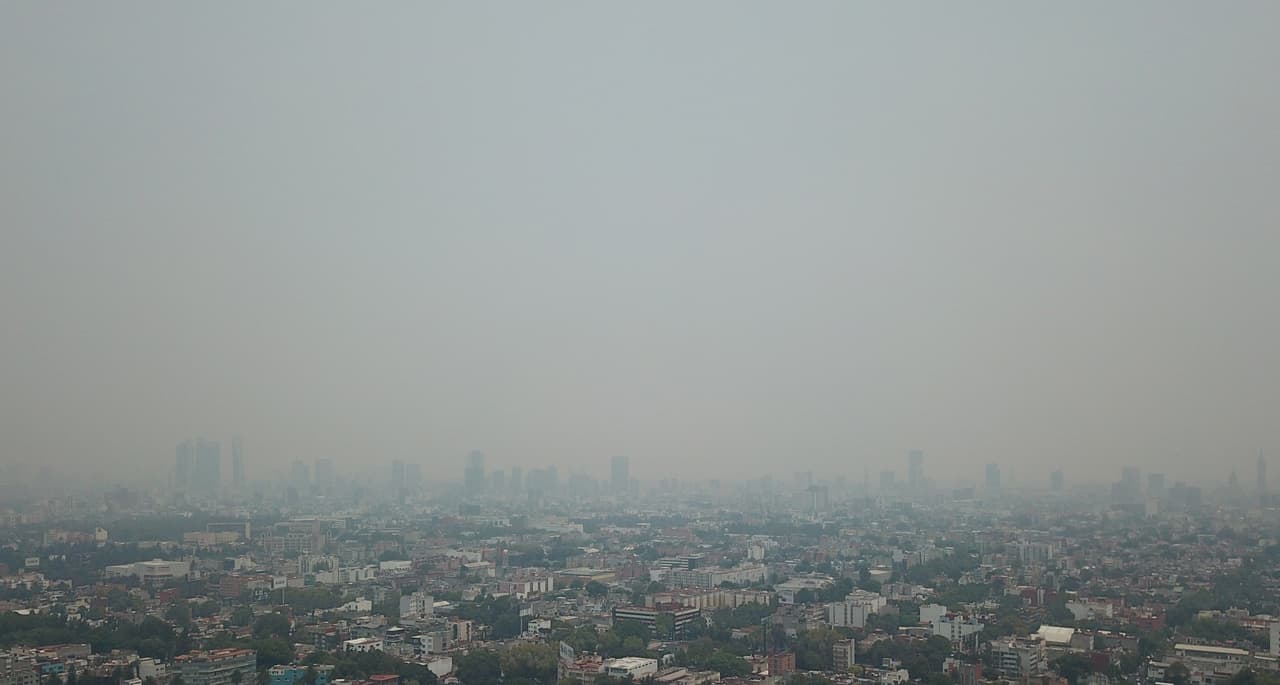 Una seri de edificios en la Ciudad de México se observan entre una espesa nube de humo.