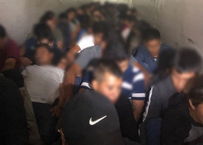 Los retenes han detectado a grupos grandes apretujados en las cajas, como los 117 indocumentados que aparecen en la foto y que fueron detenidos en un retén en Texas en octubre de 2020.