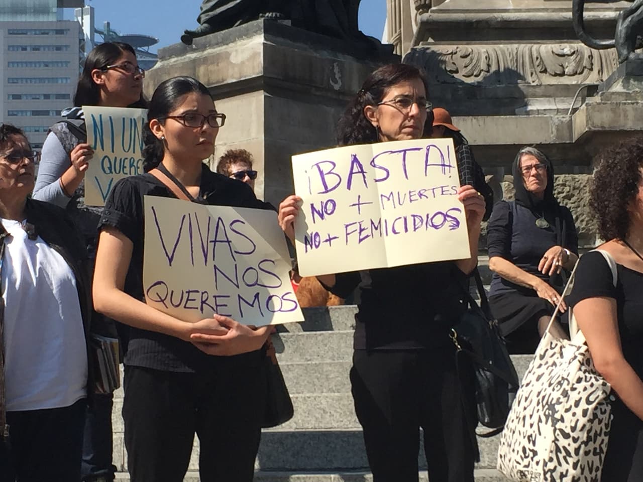 Manifestantes de vestidas de negro muestran sus pancartas.