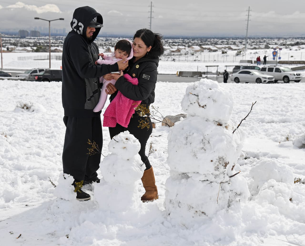 Armando García, Bella García de 7 meses y Bella García, se preparan para tomarse una foto con los muñecos de nieve que construyeron en el lado oeste de la ciudad.