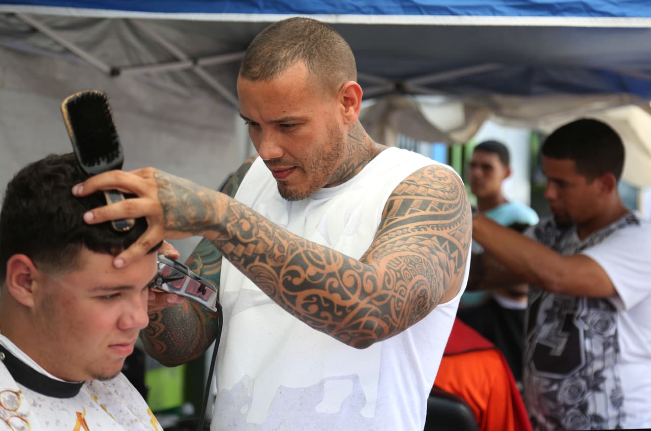 José 'Firus Cuts' Muñoz recorta a sus clientes en la acera frente a su negocio en Caguas.