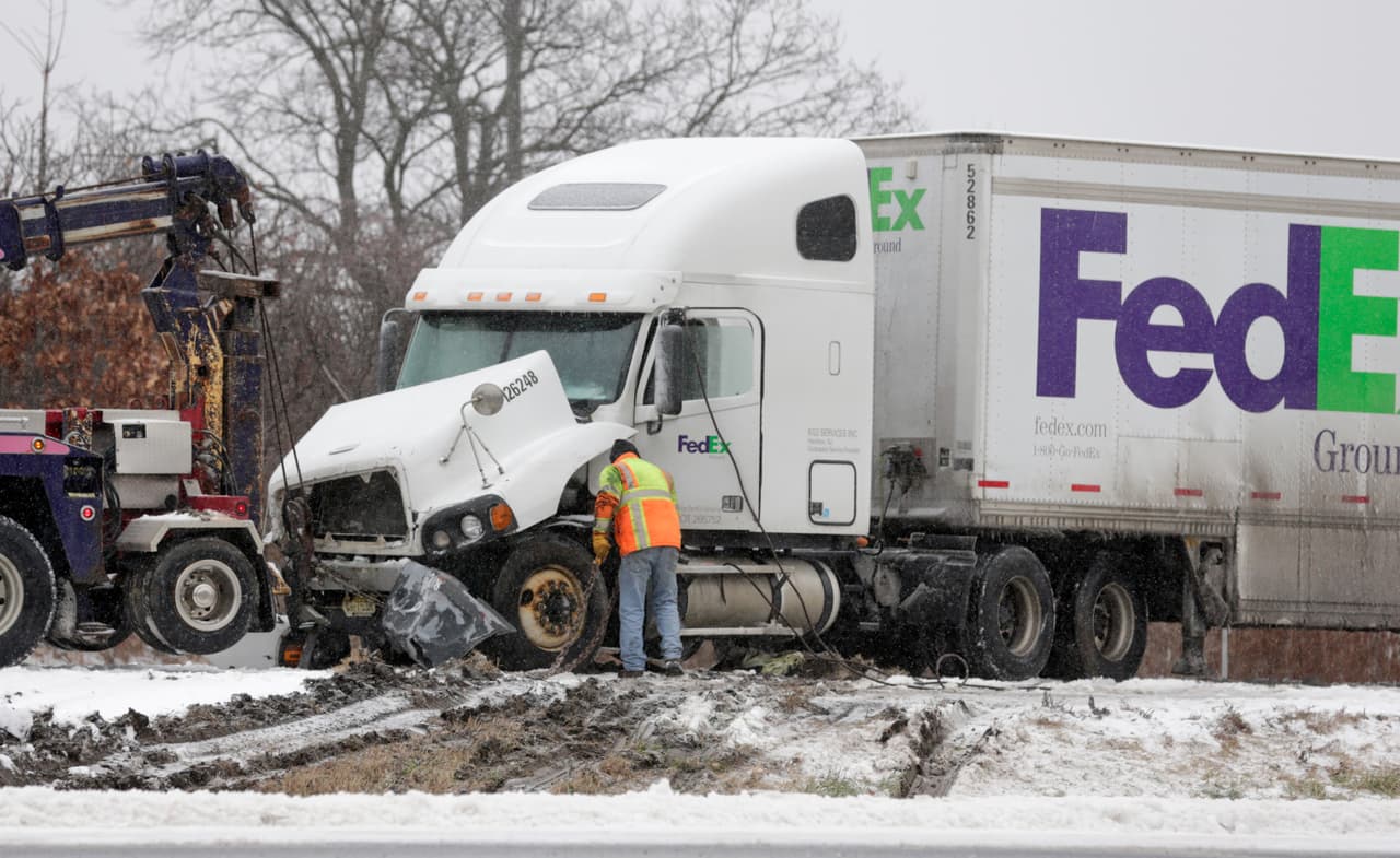 Trabajadores se preparan para remolcar un camión de FedEx que estuvo involucrado en un accidente
