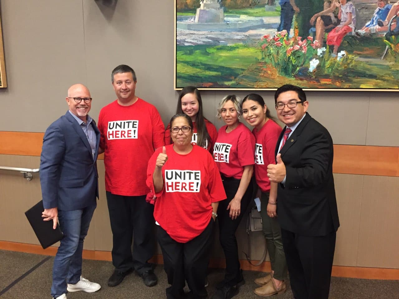 El vicealcalde de Sacramento, Eric Guerra (a la derecha) celebra con los empleados de hoteles que la ordenanza para proporcionarles el botón de pánico haya sido aprobada.