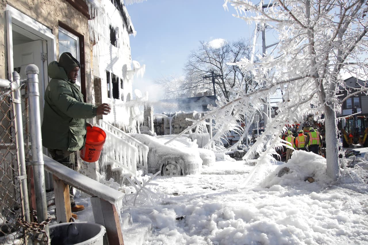 Un residente de Newark, Nueva Jersey, pone sal en la entrada de su casa para evitar la congelación. Horas antes había sucedido un incendio que fue avivado por el viento de la tormenta en esta zona.