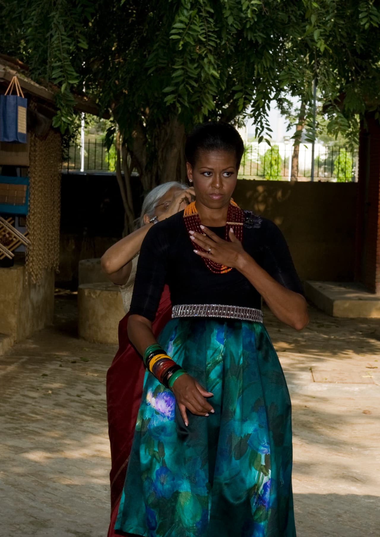 Durante su viaje de 2010 a India visitó el Museo Nacional de Manualidades y Telares de Nueva Delhi una mujer india regala a Michelle una joya de artesanía típica. La falda estampada con el cinturón estrechando la cintura conforma también un look clásico de Michelle.