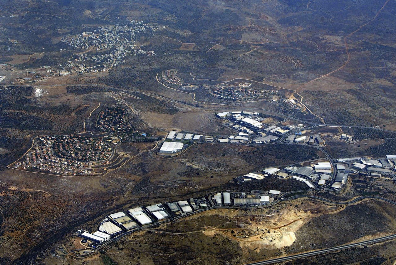 BARKAN, WEST BANK - JULY 30: The Israeli settlements of Barkan (left) and Kiryat Netafim (center) separate the Palestinian village of khirbet Bani Hassan (top left) July 30, 2004 from the of the West Bank settlement industrial area of Barkan (below). According to the left-wing Israeli movement Peace Now, some 230,000 Israelis live in 145 settlements in the West Bank and Gaza Strip, not including the scores of illegal outposts which Israel had promised the United States it would dismantle. (Photo by David Silverman/Getty Images)