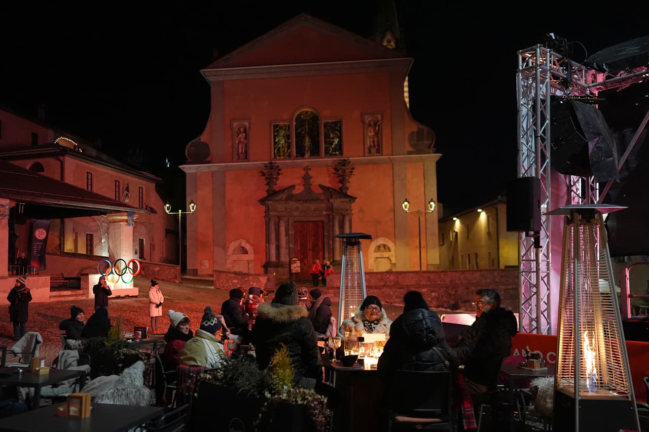 Personas abrigadas por el frío escuchan a una banda tocar en la Piazza Cavour como parte de las festividades de los Juegos Olímpicos de Invierno de 2026, en Bormio, Italia, el lunes 9 de febrero de 2026. (Foto AP/Rebecca Blackwell)